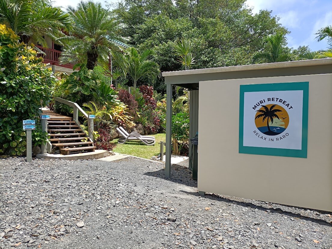 Muri Retreat entrance sign beside tropical gardens and apartment steps
