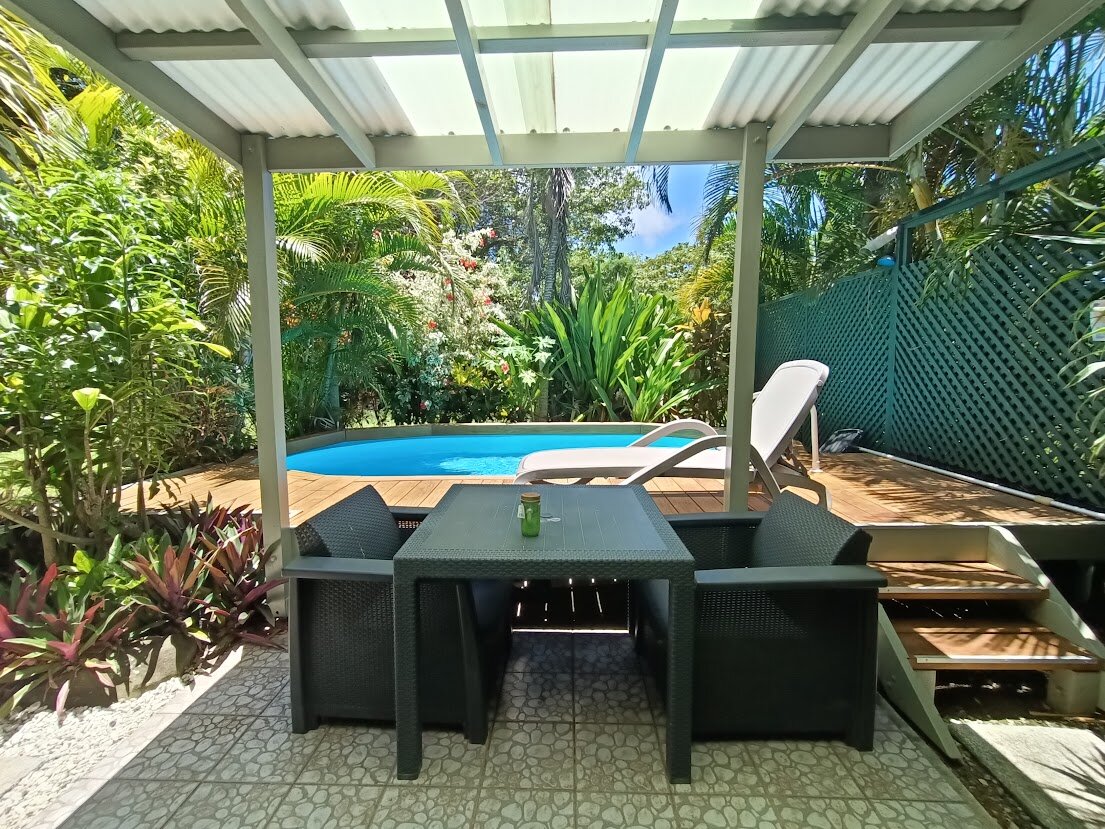 Covered outdoor dining area beside the tropical garden pool